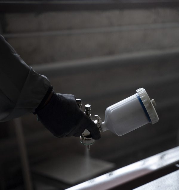 Person holding a spray gun for painting.